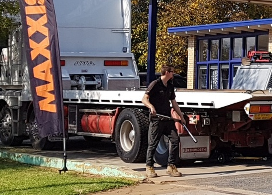 A tyre being worked on between a truck and a trailer in the yard at Kemp's Tyre Service
